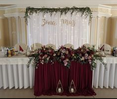 the table is set up for a wedding reception with flowers and candles on it, along with other decorations