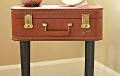 an old fashioned suitcase is sitting on a small table with a hat and other items