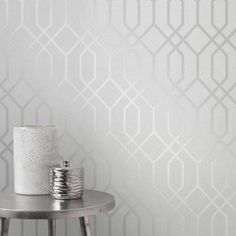 a white vase sitting on top of a table next to a wallpapered background