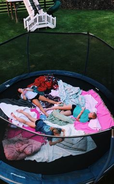 two children laying on top of clothes in a trampoline with grass behind them