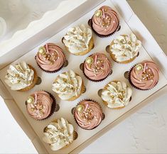 twelve cupcakes with pink frosting and gold sprinkles in a box