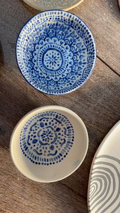 three blue and white plates sitting on top of a wooden table next to each other