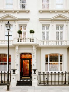 a white building with black wrought iron fence and street lamp in front of the entrance