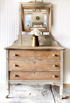 an old dresser with a mirror and vase on top