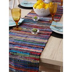 the table runner is made with multicolored yarn and has two glasses on it