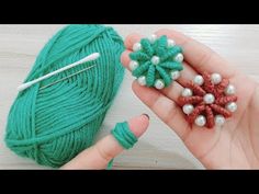 someone is knitting something with green yarn and white pearls on the tip of their fingers