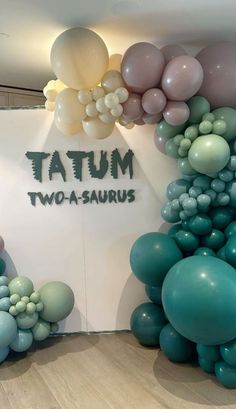 there are many balloons on the wall in front of this sign that says taum two - a - saurus