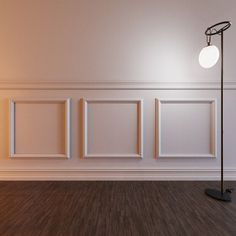 an empty room with three frames on the wall and a floor lamp next to it