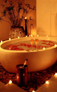 two glasses of wine sit in the middle of a bathtub with candles on it