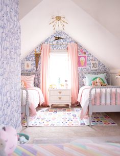 two beds in a room with pink and blue wallpaper on the walls next to each other