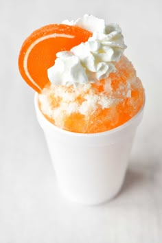 an orange dessert in a white cup with whipped cream on top and garnish