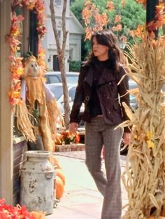 a woman is walking down the sidewalk in front of pumpkins