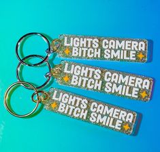 three keychains with lights on them sitting on a blue surface, one has a camera and the other is a light