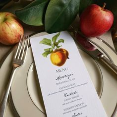 a menu card with an apple on it next to some silverware and green leaves