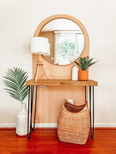 a table with a mirror, plant and basket on it in front of a window