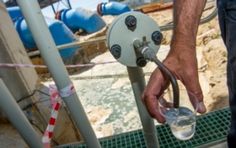 a man holding a glass in front of a machine with hoses attached to it