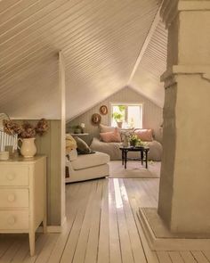 a living room with white walls and wooden flooring in the middle of an attic