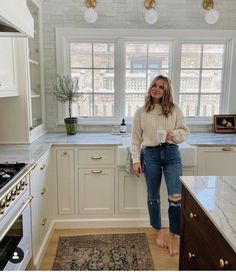 a woman standing in a kitchen next to a stove top oven