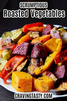 a white plate topped with roasted vegetables on top of a wooden table and text overlay that reads, scrumptious roasted vegetables