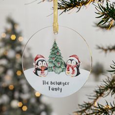 a christmas ornament hanging from a tree with penguins and a penguin on it