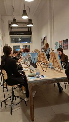 people sitting around a table with paintings on it