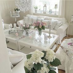 a living room with white furniture and flowers in vases on the coffee table,