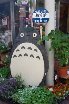 a totoro planter in front of a flower shop