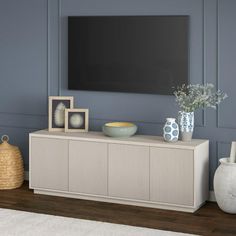 a living room with a large flat screen tv on the wall and vases in front of it