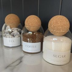 three glass jars filled with different types of sugar and coffee beans sitting on a counter