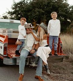 a family sitting on the back of a pickup truck