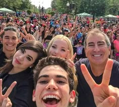 a group of people standing in front of a crowd making the peace sign with their hands