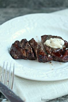 steak on a white plate with butter and fork