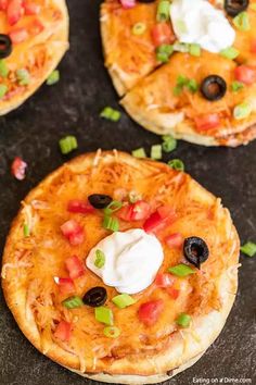 three mini pizzas with toppings on them sitting on a black counter top, ready to be eaten