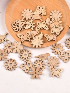 wooden cut outs with flowers and butterflies on a white surface next to a wooden spoon