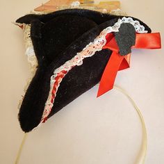 An Elope Mini Sexy Party Pirate Hat. Since Elope Has Been Sold, This May Possibly Not Being Produced Anymore And May Be A Collector's Item. Made In China For Elope, Colorado Springs. 21031k. Mini Polyester Felt Velvet Style Black Miniature Pirate Hat With White Lace Trim And Red Ribbon Bow. Elastic Stretch Band To Hold To Head. New: As Is, No Returns. See Photos For Condition, Details, And Visual Description. Product Has Been Displayed On Peg Walls/Grids At Outdoor Festivals And Indoor Store Front. Packaging May Exhibit Scuff Or Shelf Wear. See Photos. Elope Colorado, Red Beanie Hat, Peg Wall, Tweed Hat, Red Costume, Pirate Hat, Mini Hat, Velvet Style, Red Beanie