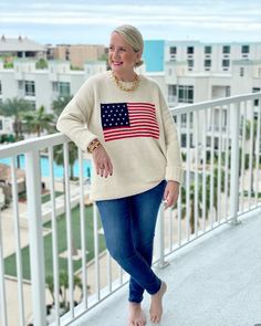 a woman standing on a balcony with an american flag sweater