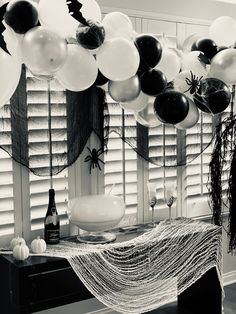 black and white balloons are hanging from the ceiling in front of a table with halloween decorations