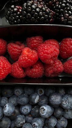 raspberries, blueberries and blackberries are displayed in metal trays on display