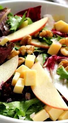 a salad with apples, walnuts and lettuce is shown in a white bowl