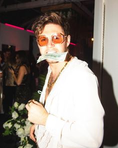 a man with sunglasses and a fake moustache on his face at a party