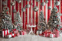 christmas trees decorated with silver, red and white ornaments in front of striped wallpaper