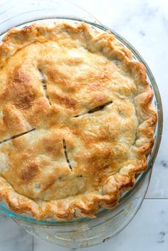 a freshly baked pie sitting on top of a glass platter next to a knife