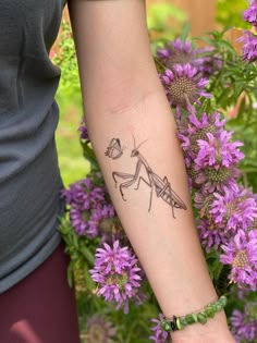 a person with a tattoo on their arm holding a purple flower in front of them