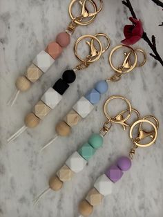 four pairs of keychains with different colors and shapes are on a marble surface