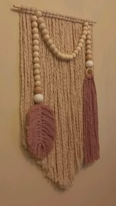 macrame wall hanging with wooden beads and tassels on beige background, closeup