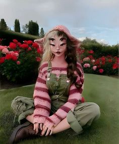 a doll is sitting on the ground in front of flowers and grass with her eyes closed