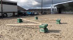 there are several wooden poles laying on the ground in front of some trucks and buildings