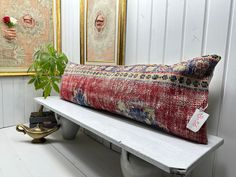 a white bench with a pillow on it and a potted plant next to it