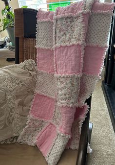 a pink and white blanket sitting on top of a bed