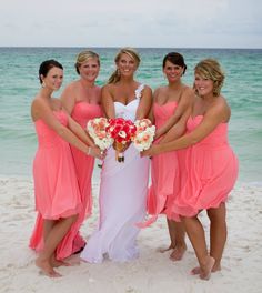 four bridesmaids pose on the beach with their bouquets in front of them